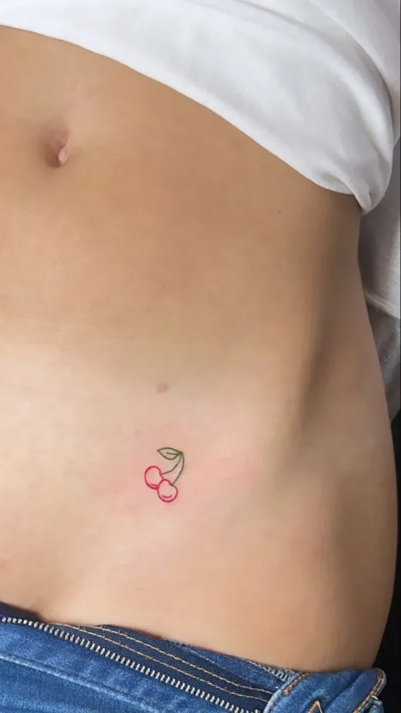 Tatouage cerise coloré sur le bas du ventre d'une femme