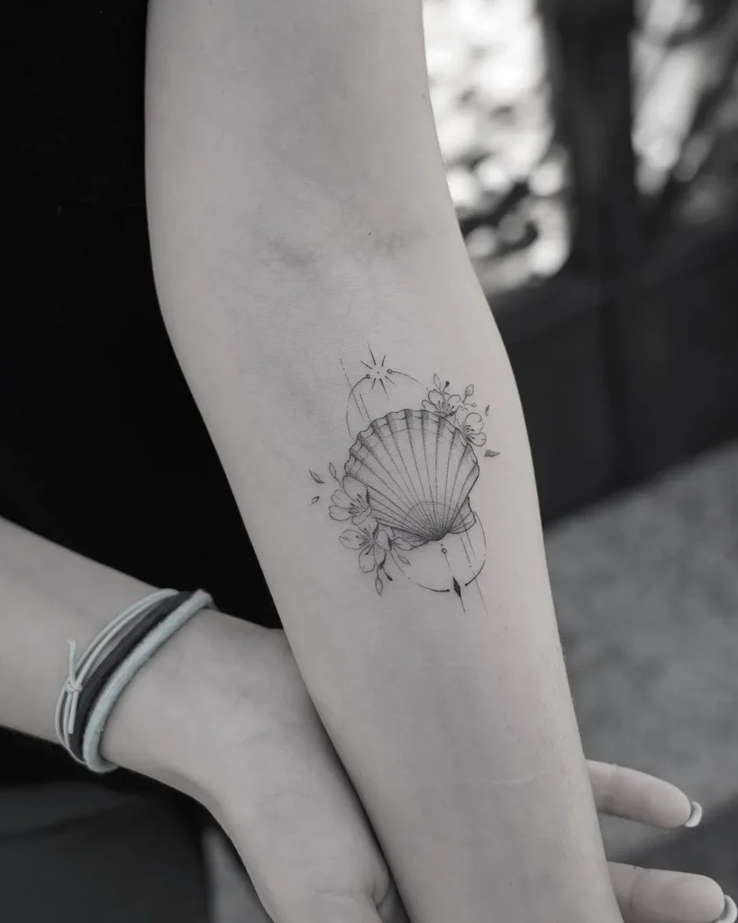 Tatouage coquillage avec des fleurs sur le bras d'une femme