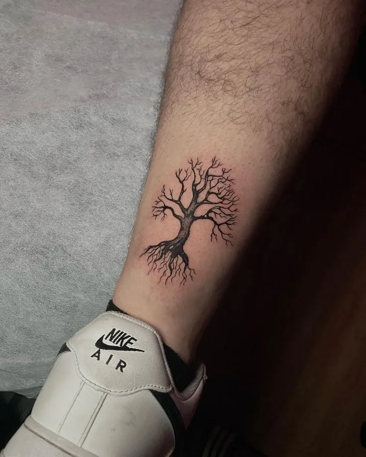 Tatouage d'un arbre à l'arrière de la jambe d'un homme, symbole de force