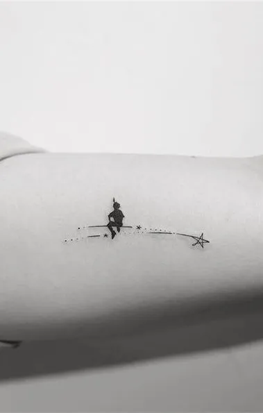 Tatouage minimaliste d'une étoile filante avec une personne assise dessus
