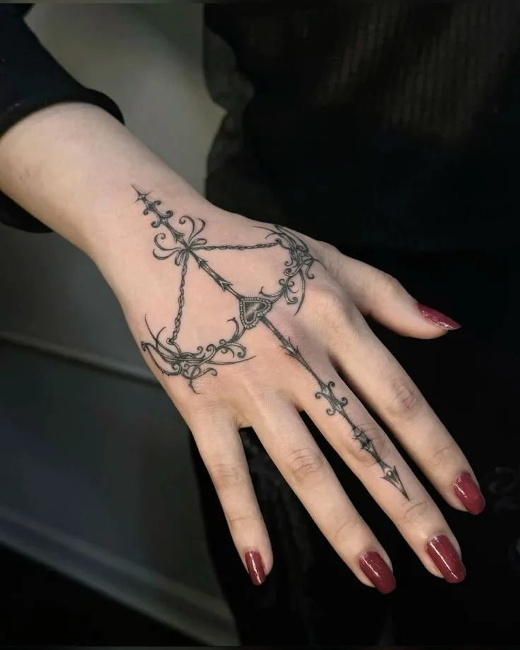 Tatouage flèche avec un arc sur la main d'une femme