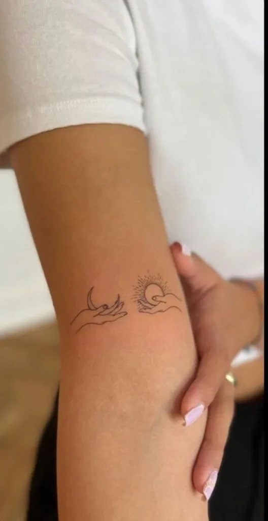Tatouage lune et soleil reposant respectivement sur une main