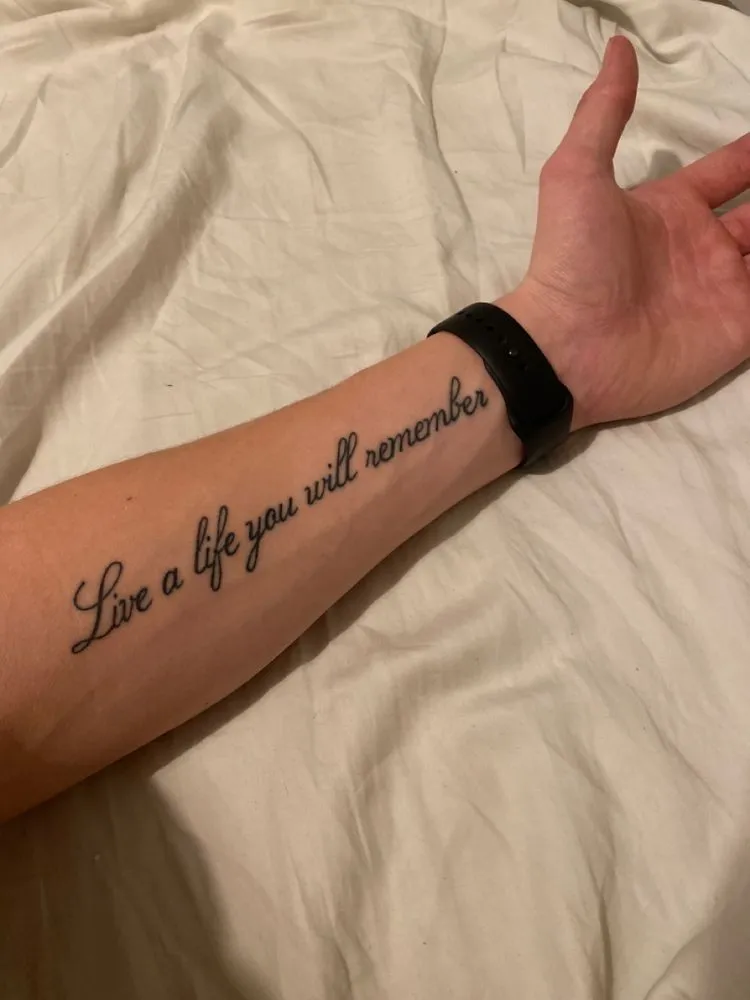 Tatouage d'une phrase en anglais sur l'avant bras d'un homme