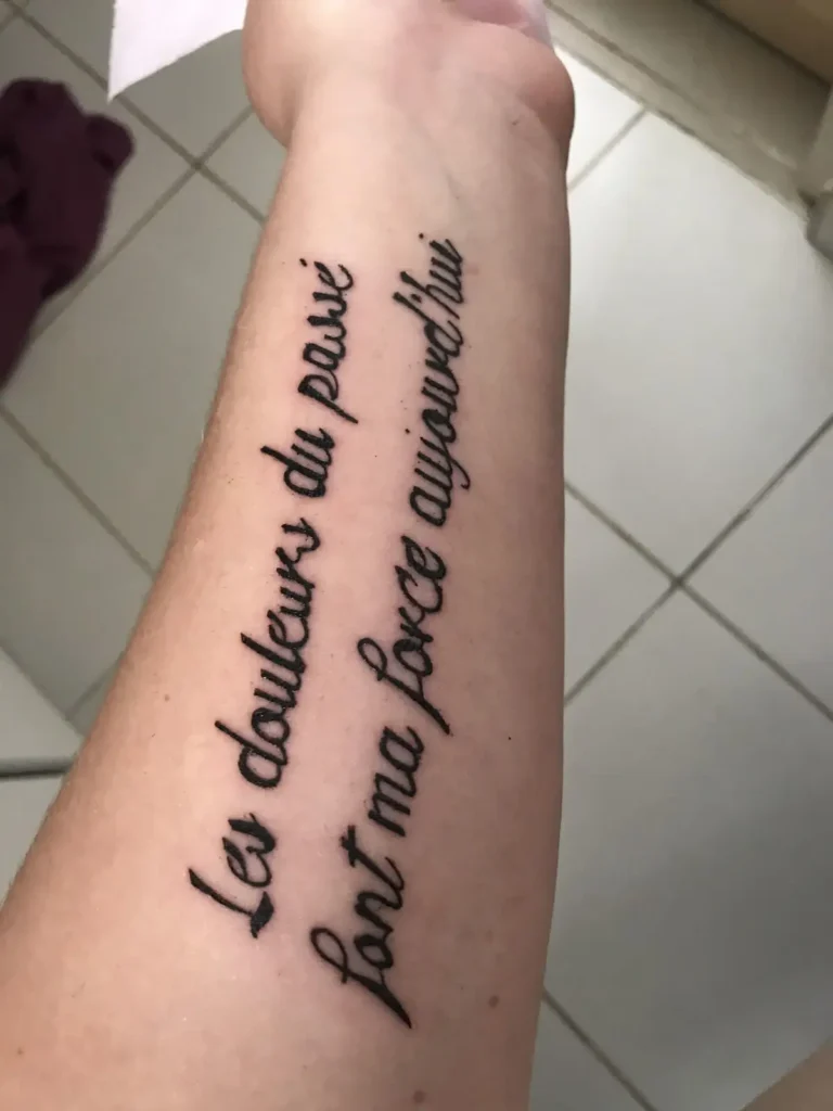 Tatouage d'une phrase en français sur l'avant bras d'un homme