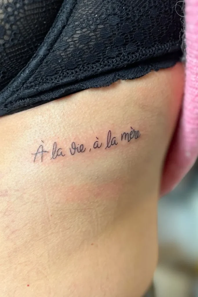 Tatouage phrase en français sous la poitrine d'une femme