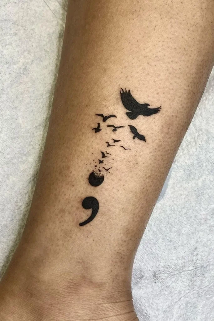 Tatouage point virgule s'effaçant doucement pour laisser s'envoler des oiseaux
