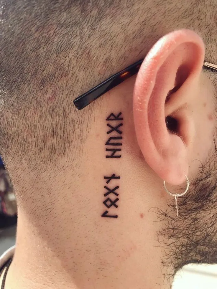 Tatouage de runes viking derrière l'oreille d'un homme
