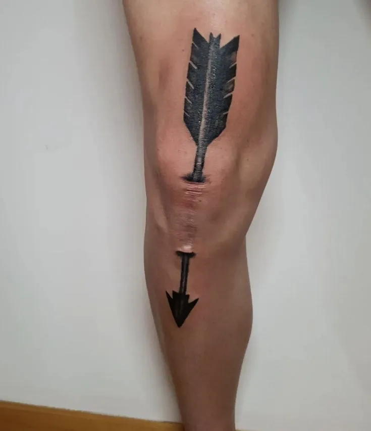 Tatouage sur une cicatrice représentant une flèche traversant le genoux