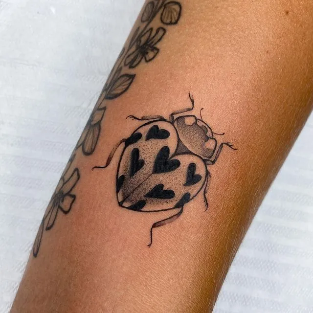 Tatouage coccinelle avec des cœurs sur le bras