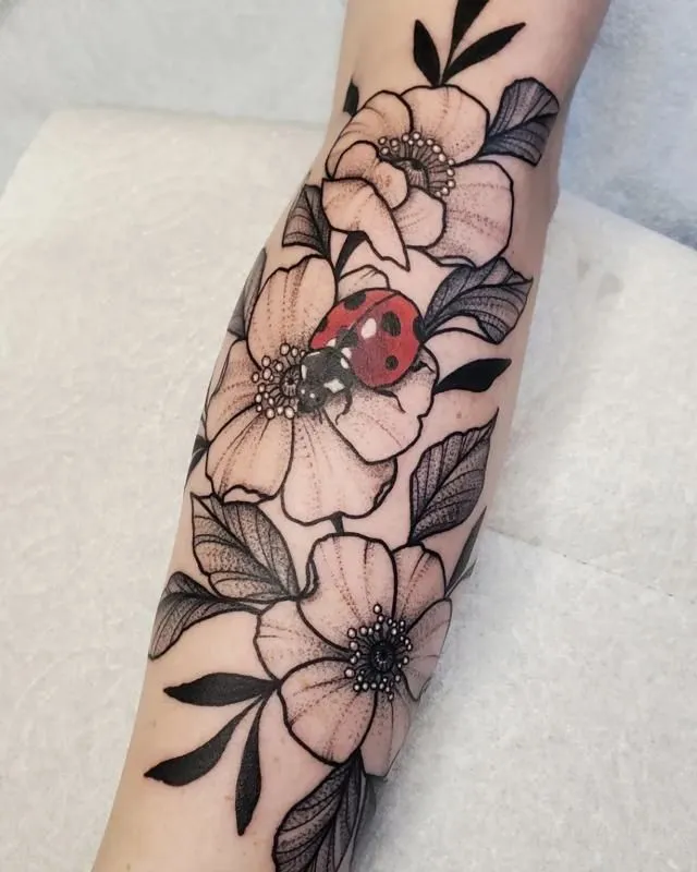 Tatouage d'une coccinelle rouge sur des fleurs