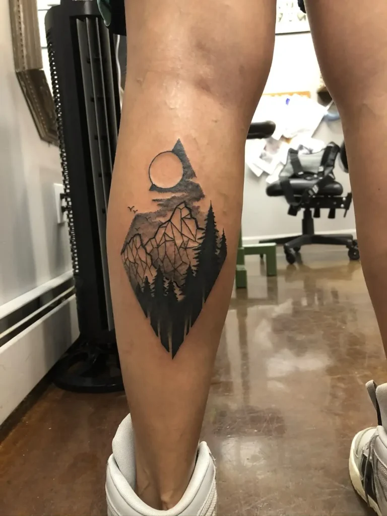 Tatouage montagne géométrique et réaliste sur le mollet 